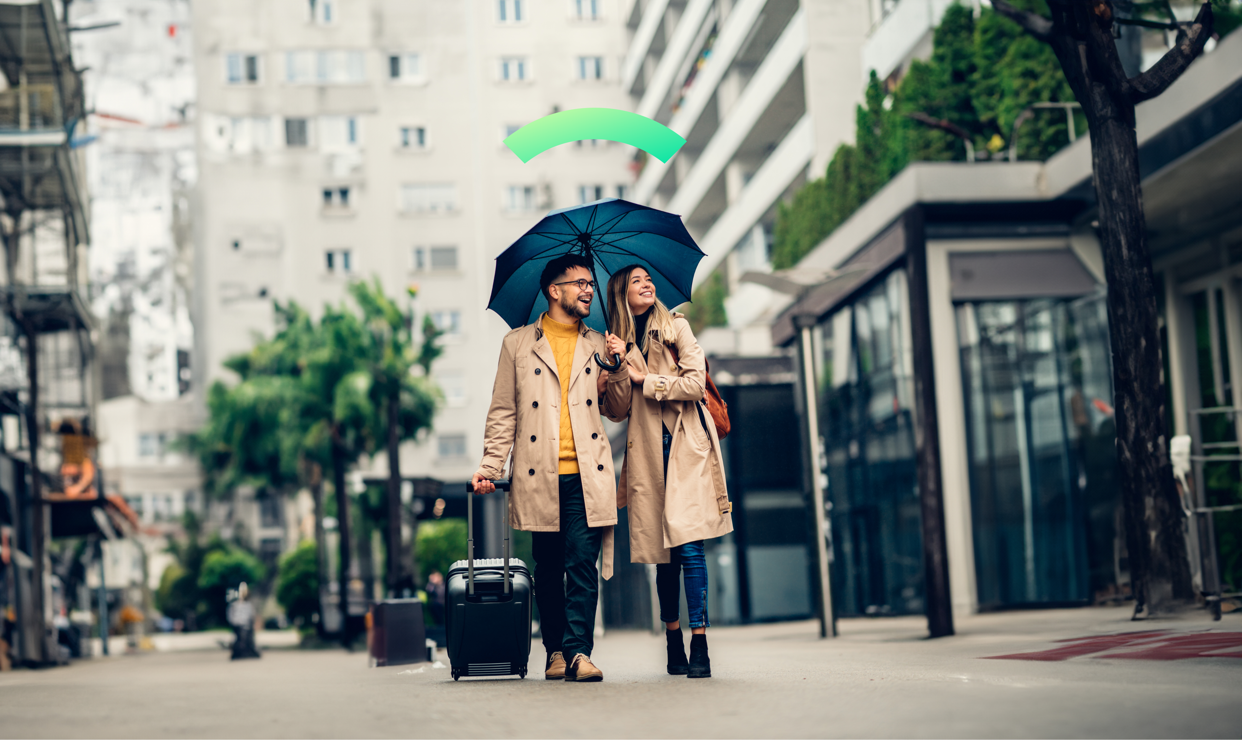 A couple walks down a city street holding an umbrella. They're Covered.