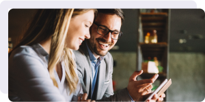 Two professionals smile as they look at a phone.